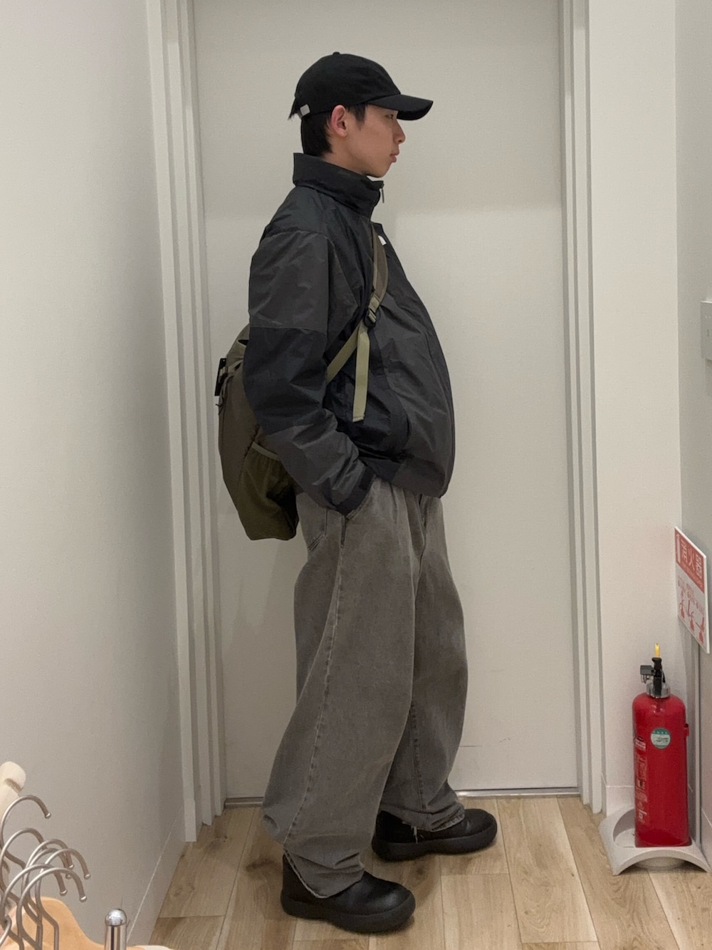 グレー系のブルゾン、グリーン系のショルダーバッグ、ブラック系のキャップを着用したメンズの春コーディネートの2枚目の写真