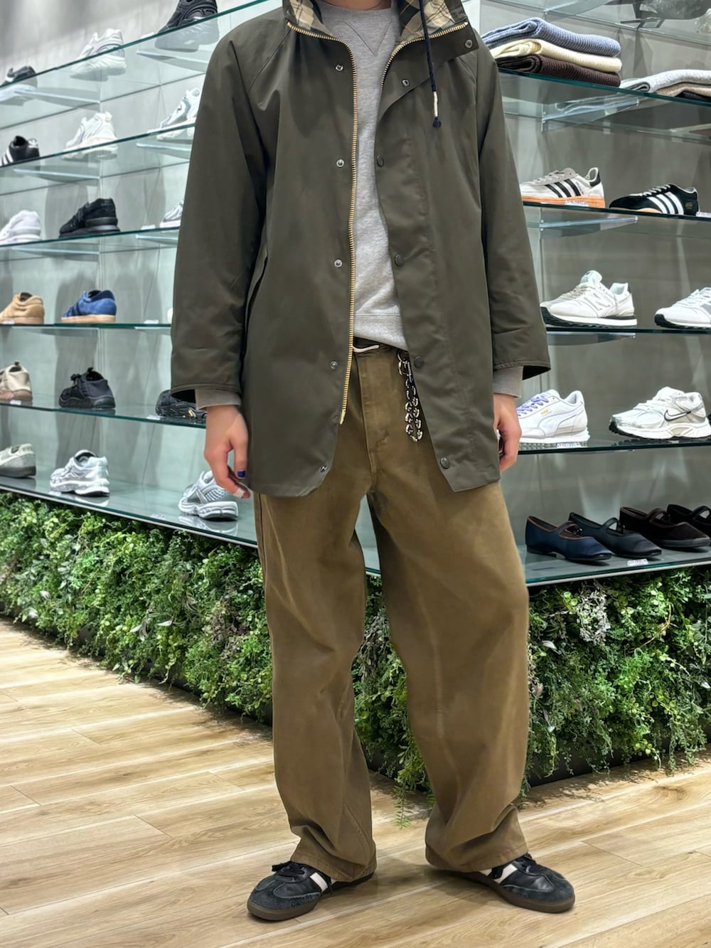 グリーン系のモッズコート、ブラウン系のデニムパンツ、ブラック系のスニーカーを着用したメンズの秋コーディネートの4枚目の写真