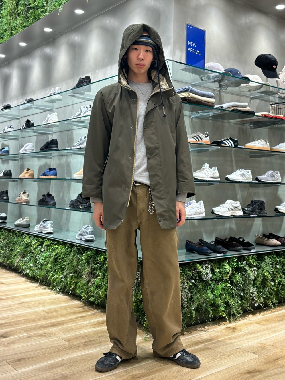 グリーン系のモッズコート、ブラウン系のデニムパンツ、ブラック系のスニーカーを着用したメンズの秋コーディネートの2枚目の写真