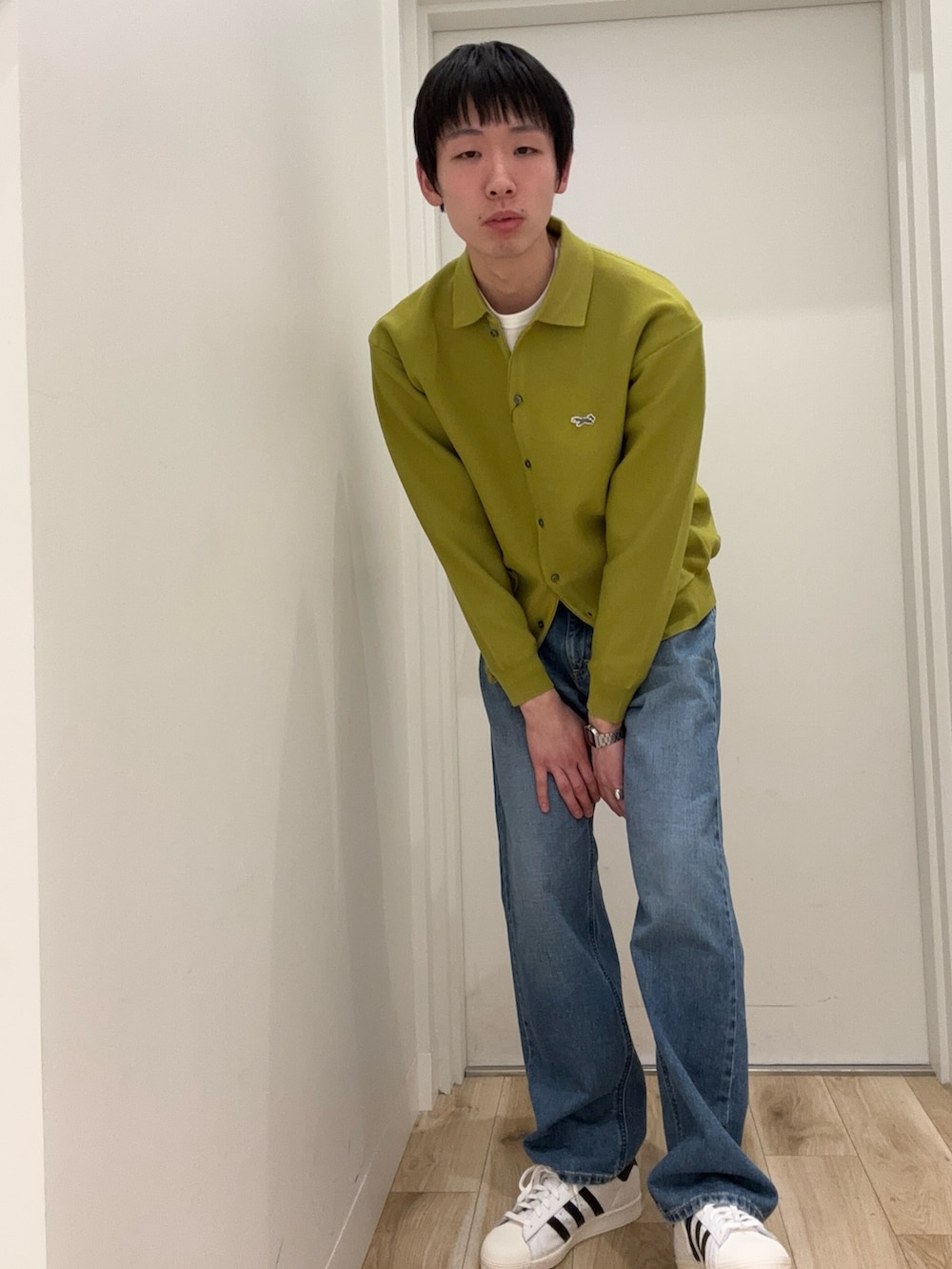 イエロー系のカーディガン/ボレロ、ブルー系のデニムパンツ、ホワイト系のスニーカーを着用したメンズの冬コーディネートの2枚目の写真