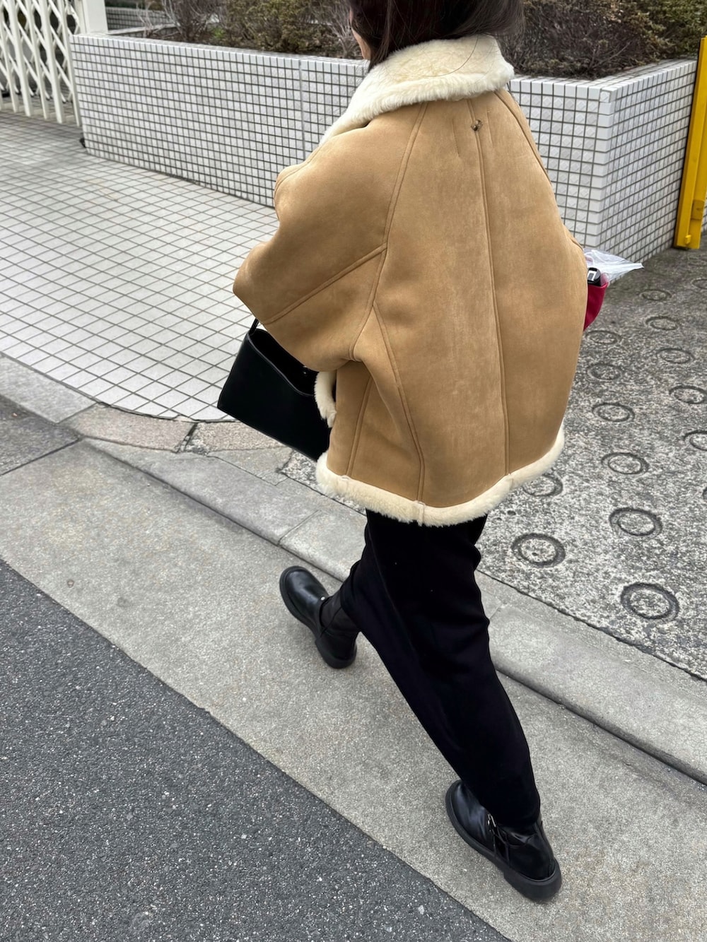 ベージュ系のムートンコートを着用したレディースの冬コーディネートの2枚目の写真