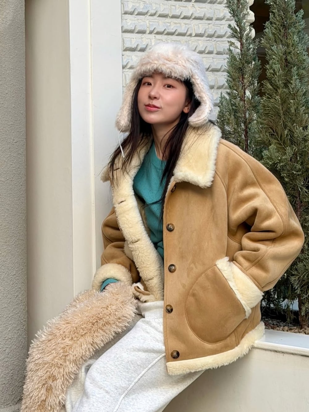 ベージュ系のムートンコートを着用したレディースの冬コーディネートの3枚目の写真