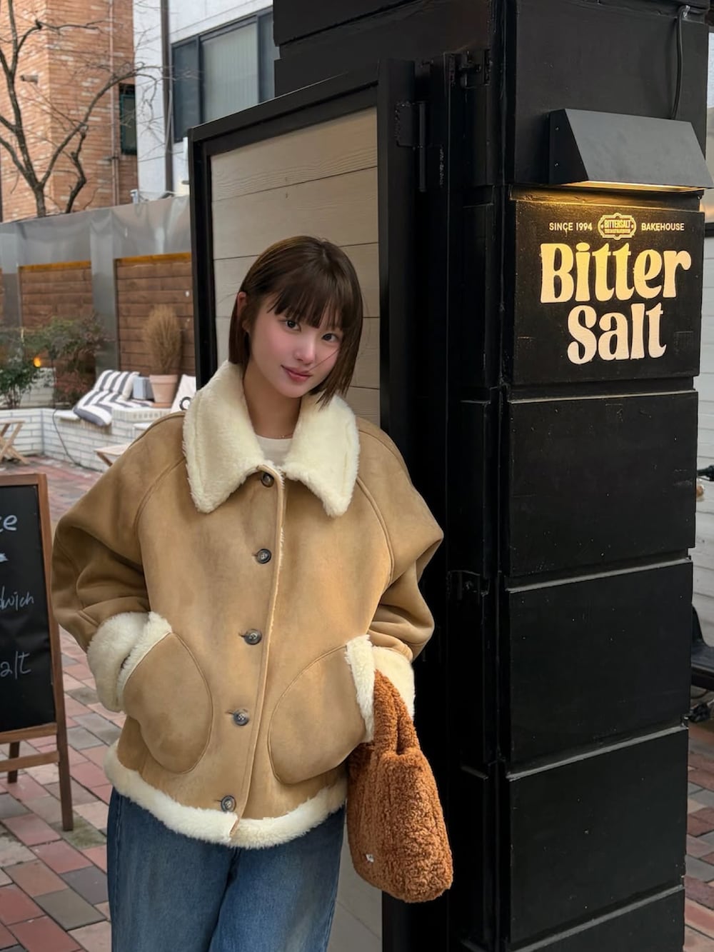 ベージュ系のムートンコートを着用したレディースの冬コーディネートの2枚目の写真