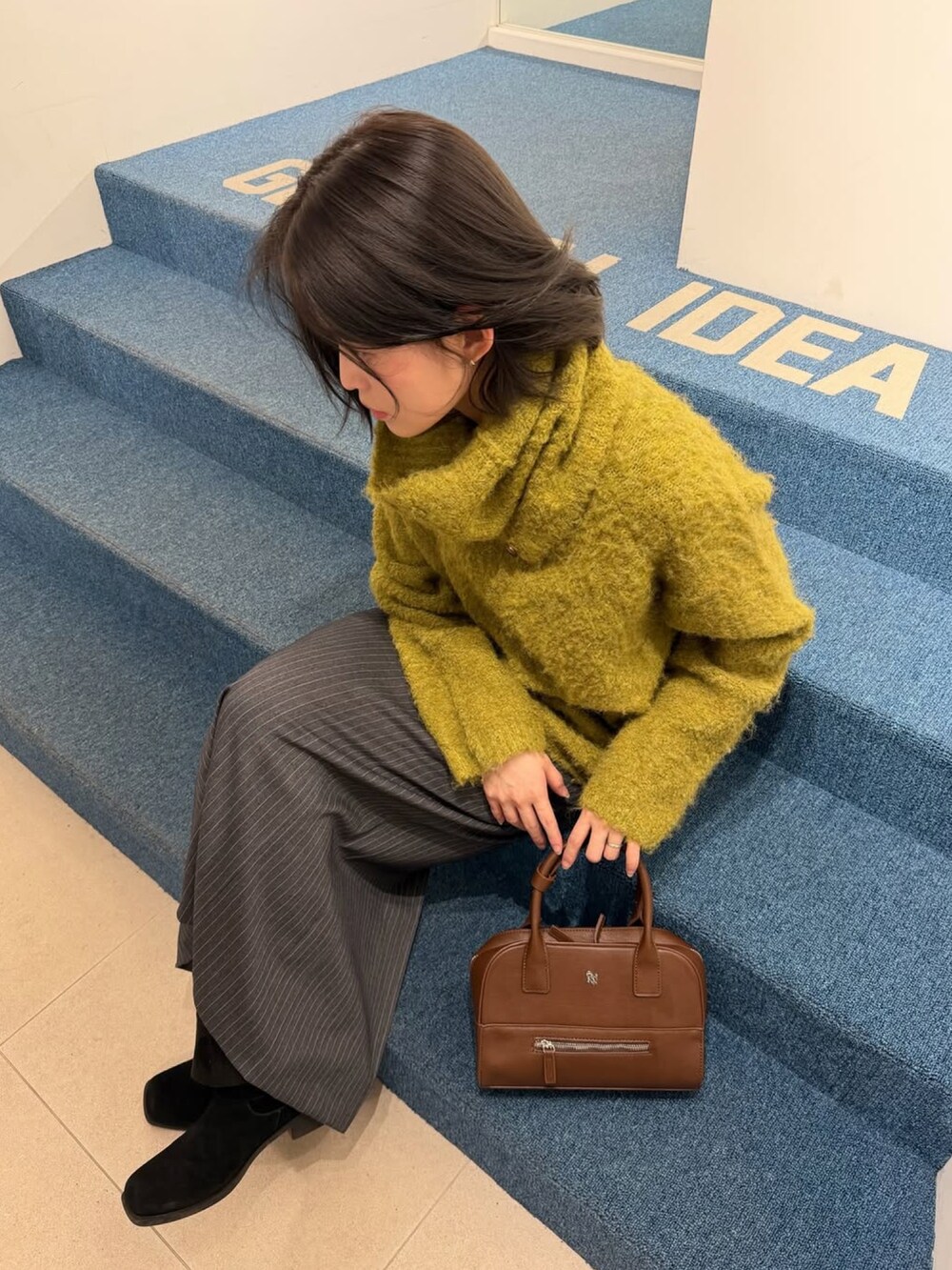 ブラウン系のトートバッグを着用したレディースの冬コーディネートの2枚目の写真