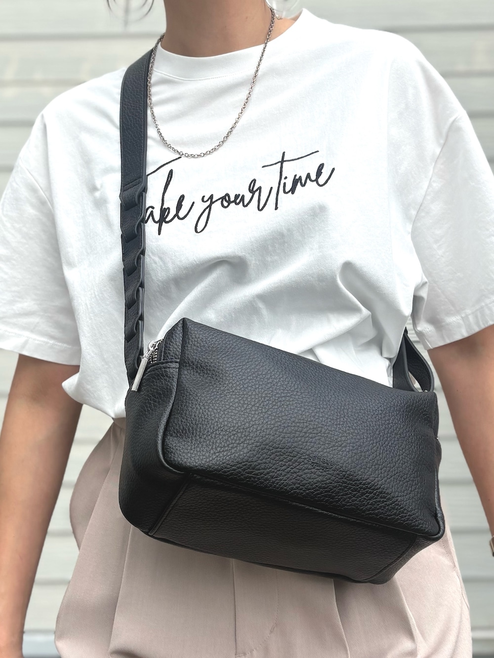 ベージュ系のスラックス、ホワイト系のTシャツ/カットソーを着用したレディースの夏コーディネートの3枚目の写真