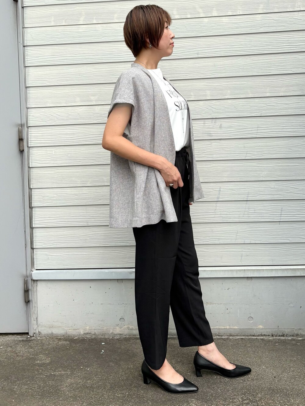 ベージュ系のノーカラージャケット、ブラック系のその他パンツ、シルバー系のネックレスを着用したレディースの夏コーディネートの2枚目の写真