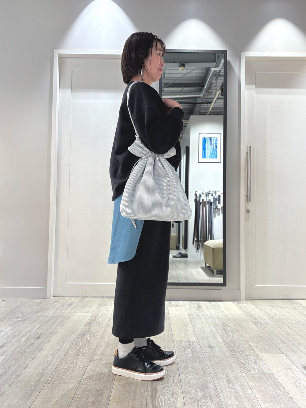 ブラック系のスウェット、ブラック系のスカート、ブルー系のシャツ/ブラウスを着用したレディースの春コーディネートの2枚目の写真