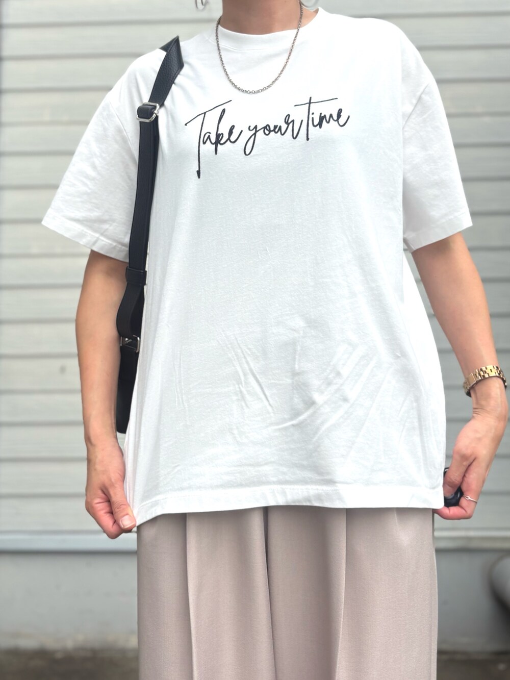 ベージュ系のスラックス、ホワイト系のTシャツ/カットソーを着用したレディースの夏コーディネートの4枚目の写真