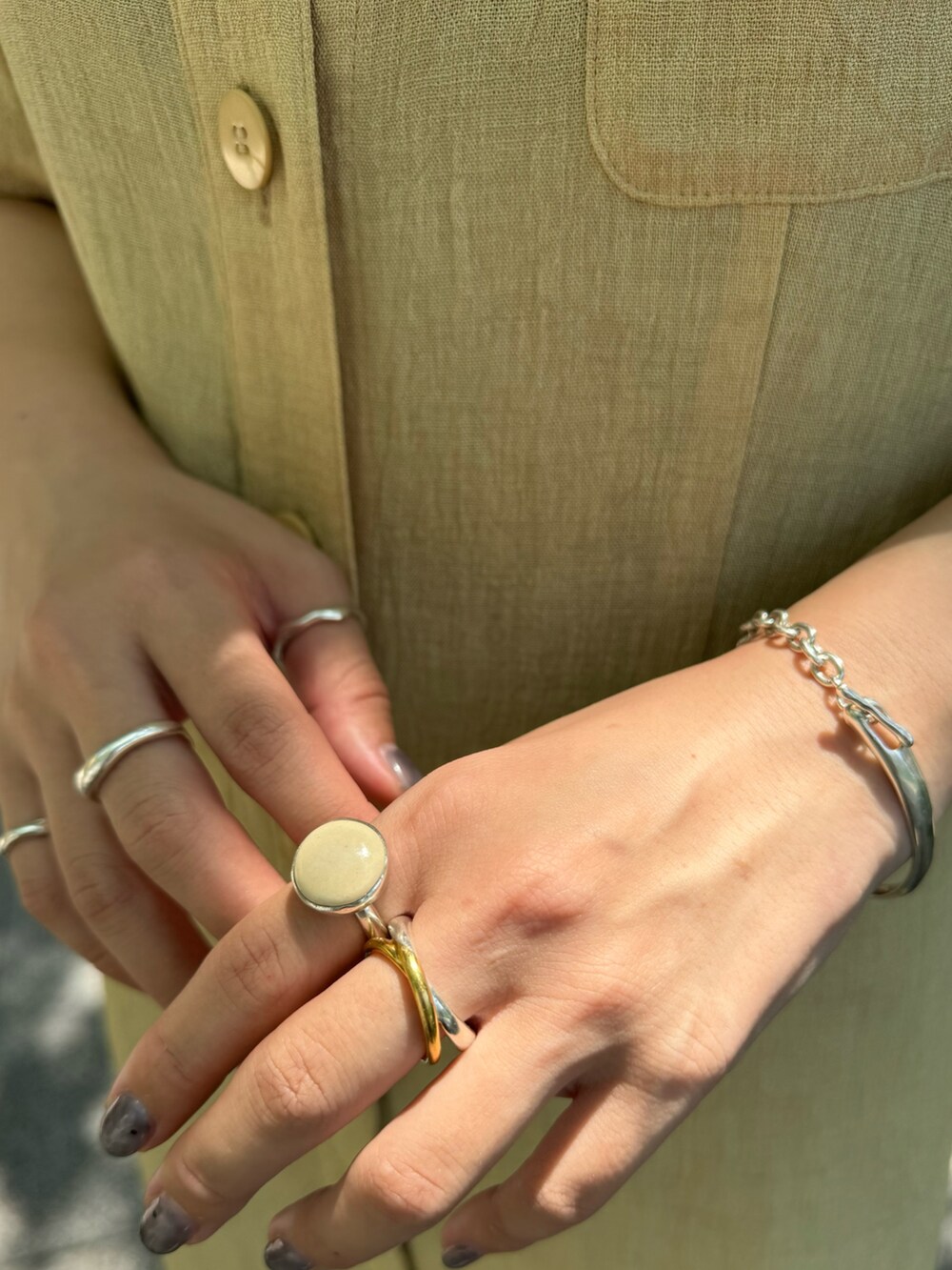 シルバー系のブレスレット、ベージュ系のリング、ゴールド系のネックレスを着用したレディースの夏コーディネートの2枚目の写真