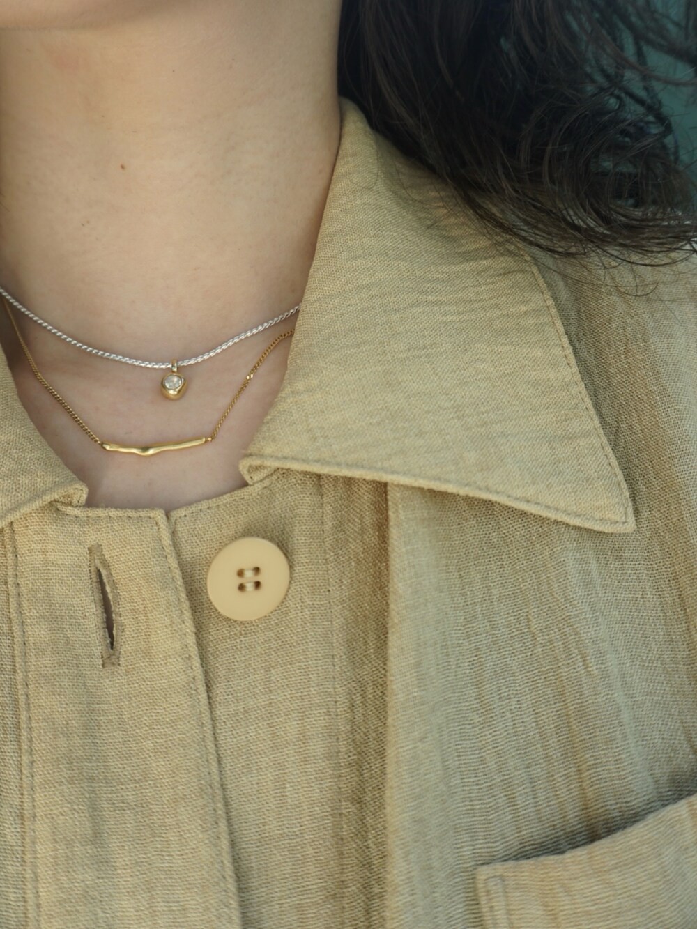 シルバー系のブレスレット、ベージュ系のリング、ゴールド系のネックレスを着用したレディースの夏コーディネートの3枚目の写真