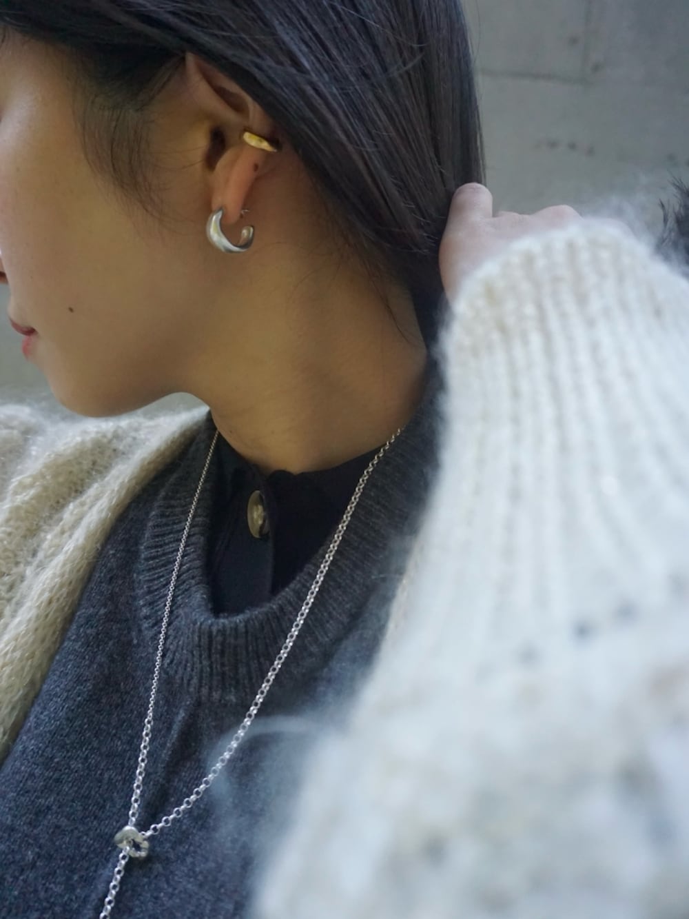 シルバー系のピアス（両耳用）、シルバー系のネックレス、ゴールド系のイヤーカフを着用したレディースの冬コーディネートの2枚目の写真