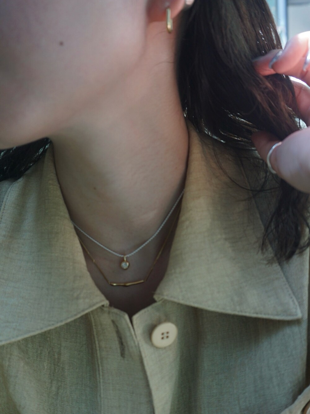 シルバー系のブレスレット、ベージュ系のリング、ゴールド系のネックレスを着用したレディースの夏コーディネートの5枚目の写真