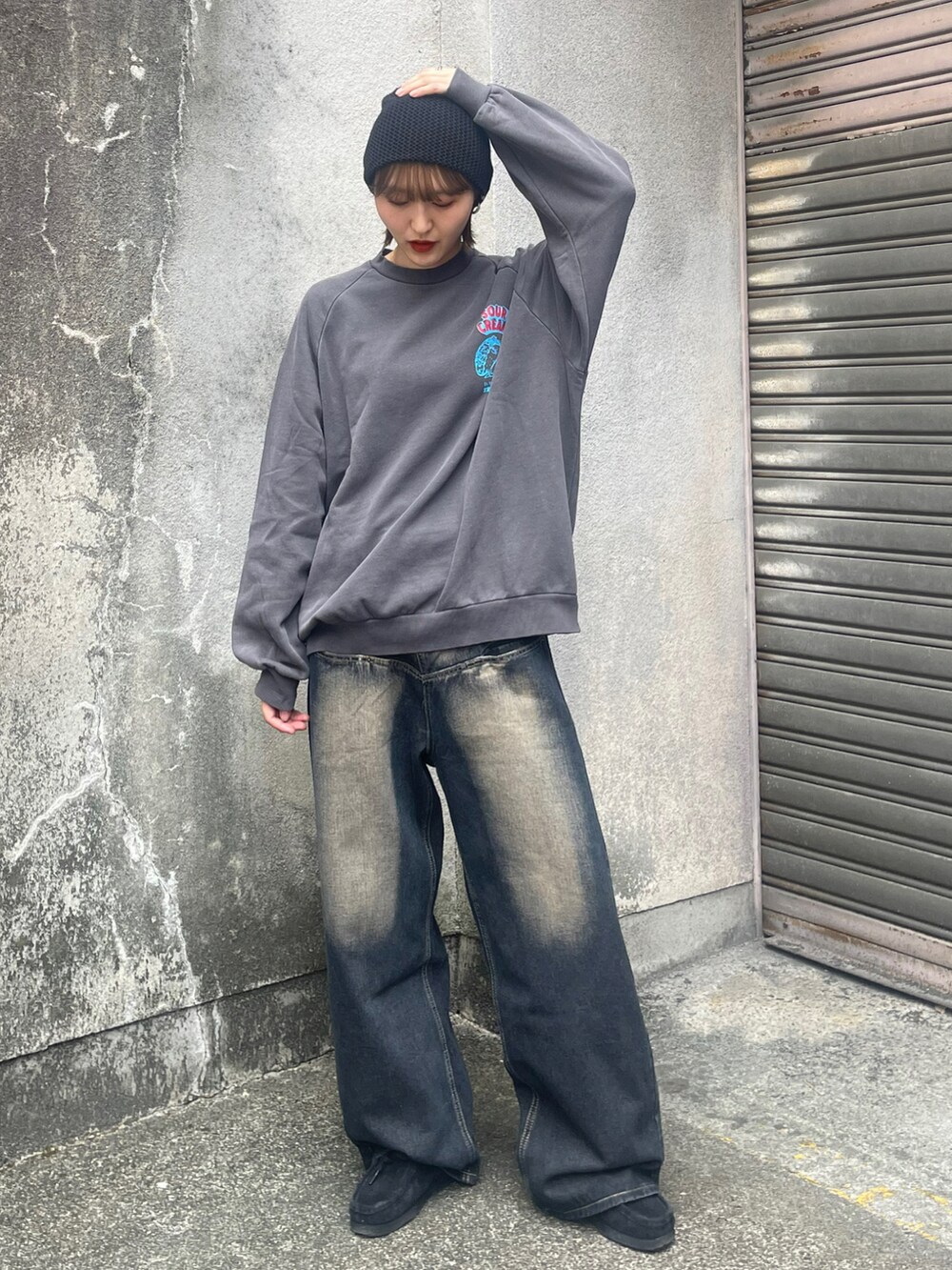 ブラック系のスウェット、ブルー系のデニムパンツ、ブラック系のブーツを着用したレディースの夏コーディネートの2枚目の写真