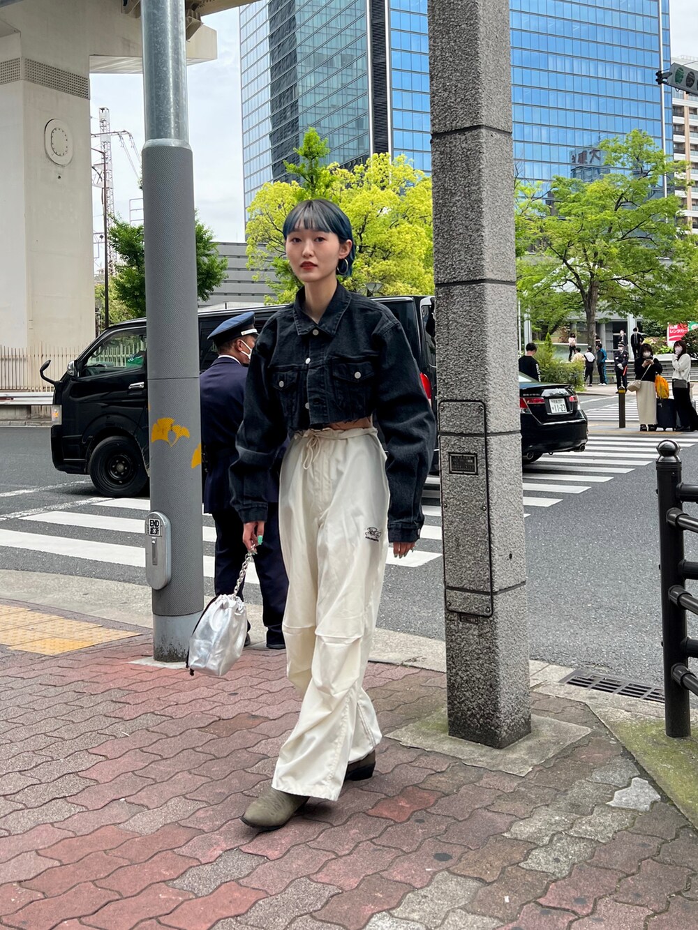 ブラック系のデニムジャケット、ホワイト系のカーゴパンツ、シルバー系のハンドバッグを着用したレディースの春コーディネートの2枚目の写真