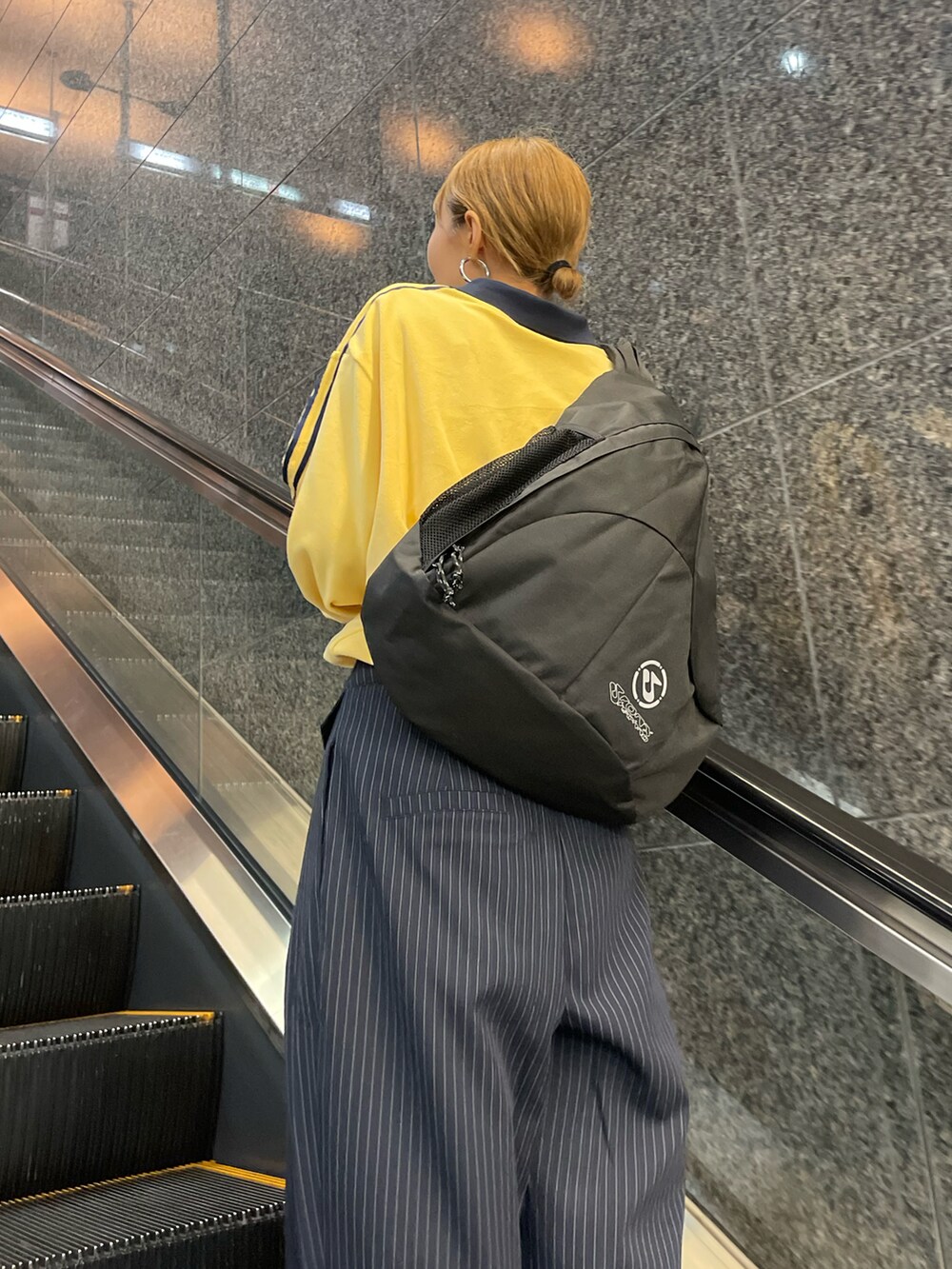 イエロー系のスウェット、ブルー系のスラックス、ブラック系のバックパック/リュックを着用したレディースの秋コーディネートの3枚目の写真