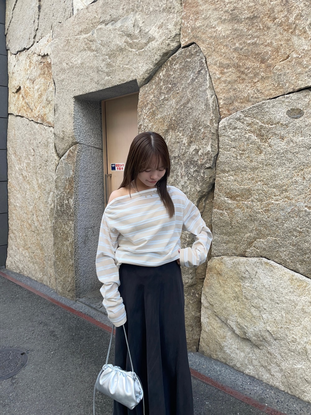 ベージュ系のTシャツ/カットソー、ブラック系のスカート、シルバー系のショルダーバッグを着用したレディースの春コーディネートの7枚目の写真