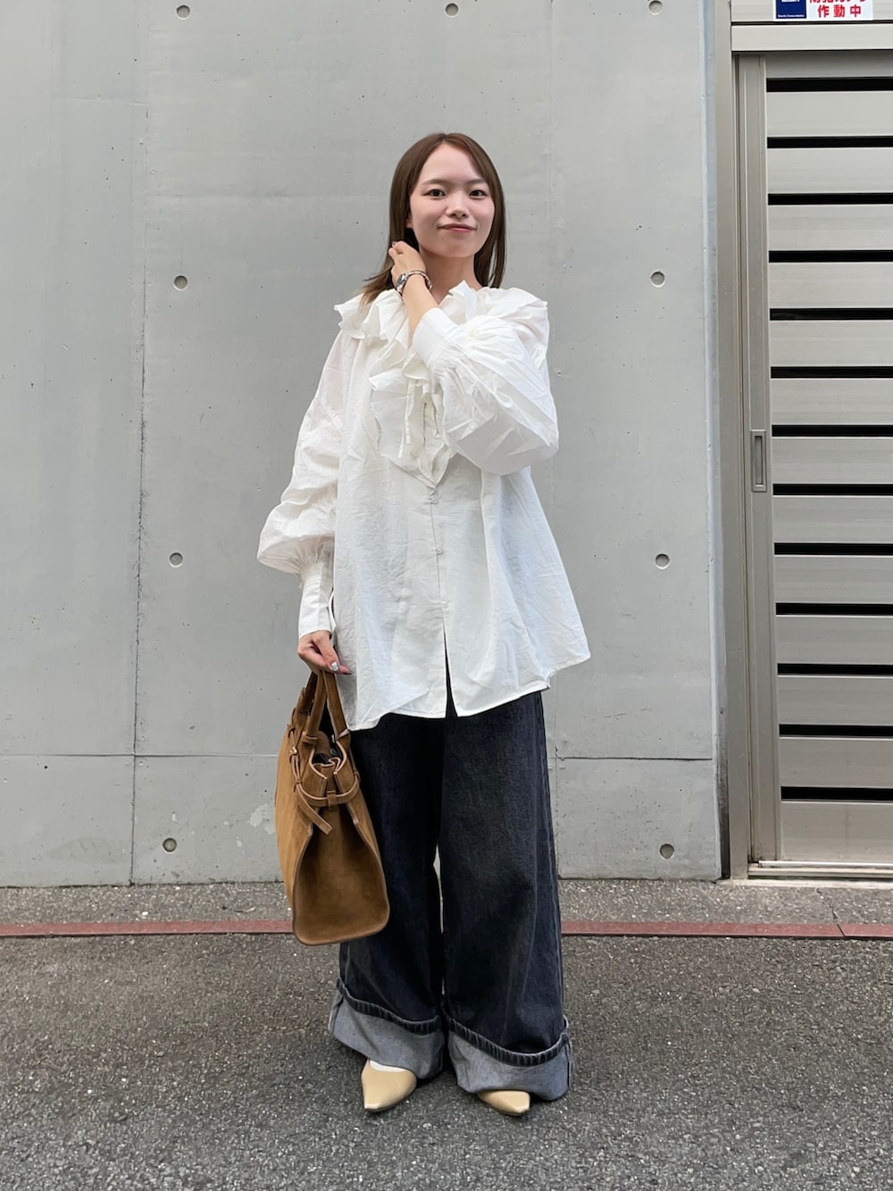 ブラウン系のトートバッグ、ブラック系のデニムパンツ、ベージュ系のパンプスを着用したレディースの秋コーディネートの6枚目の写真