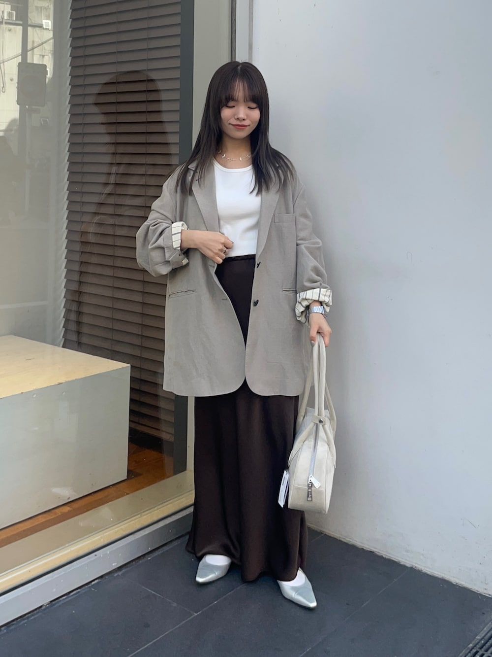 ベージュ系のその他アウター、ブラウン系のスカート、ホワイト系のタンクトップを着用したレディースの春コーディネートの2枚目の写真