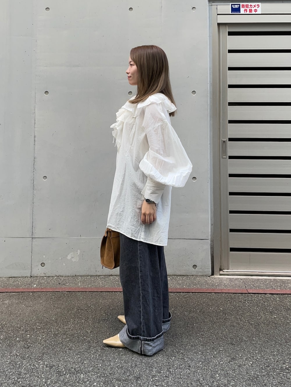 ブラウン系のトートバッグ、ブラック系のデニムパンツ、ベージュ系のパンプスを着用したレディースの秋コーディネートの5枚目の写真