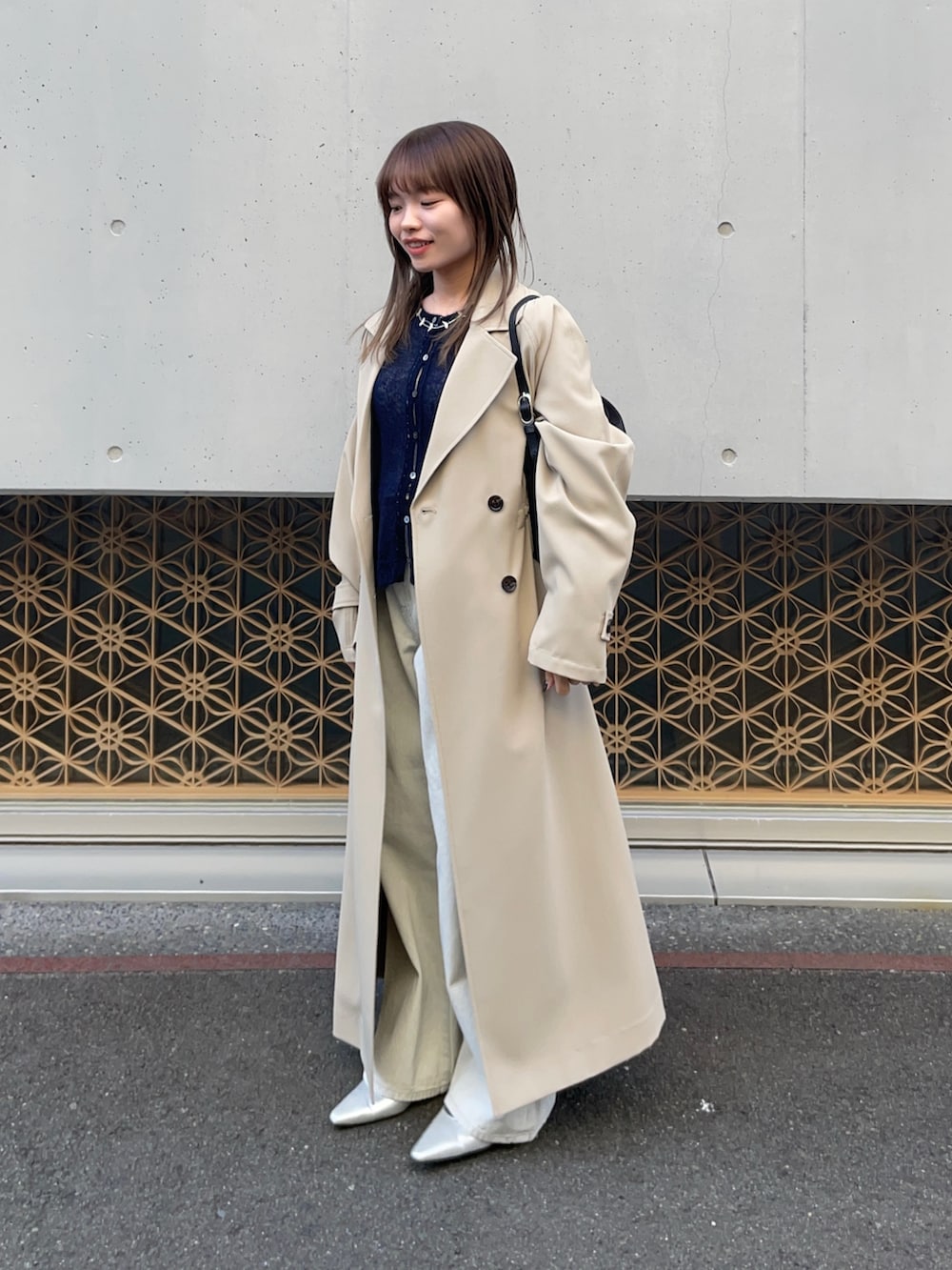 ベージュ系のトレンチコート、ブルー系のカーディガン/ボレロ、グレー系のデニムパンツを着用したレディースの冬コーディネートの3枚目の写真