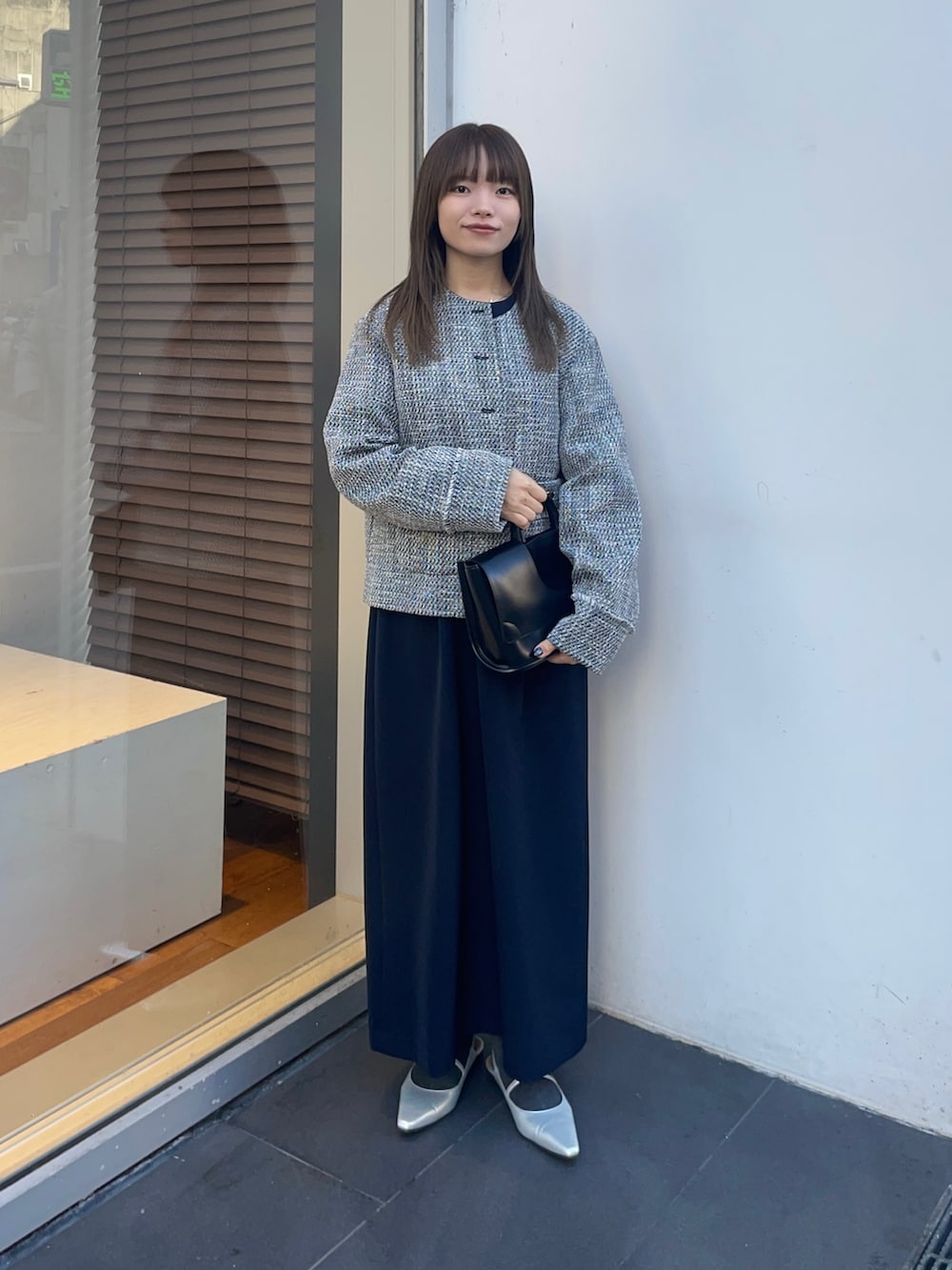 ブラック系のノーカラージャケット、ブルー系のワンピース、シルバー系のパンプスを着用したレディースの冬コーディネートの6枚目の写真