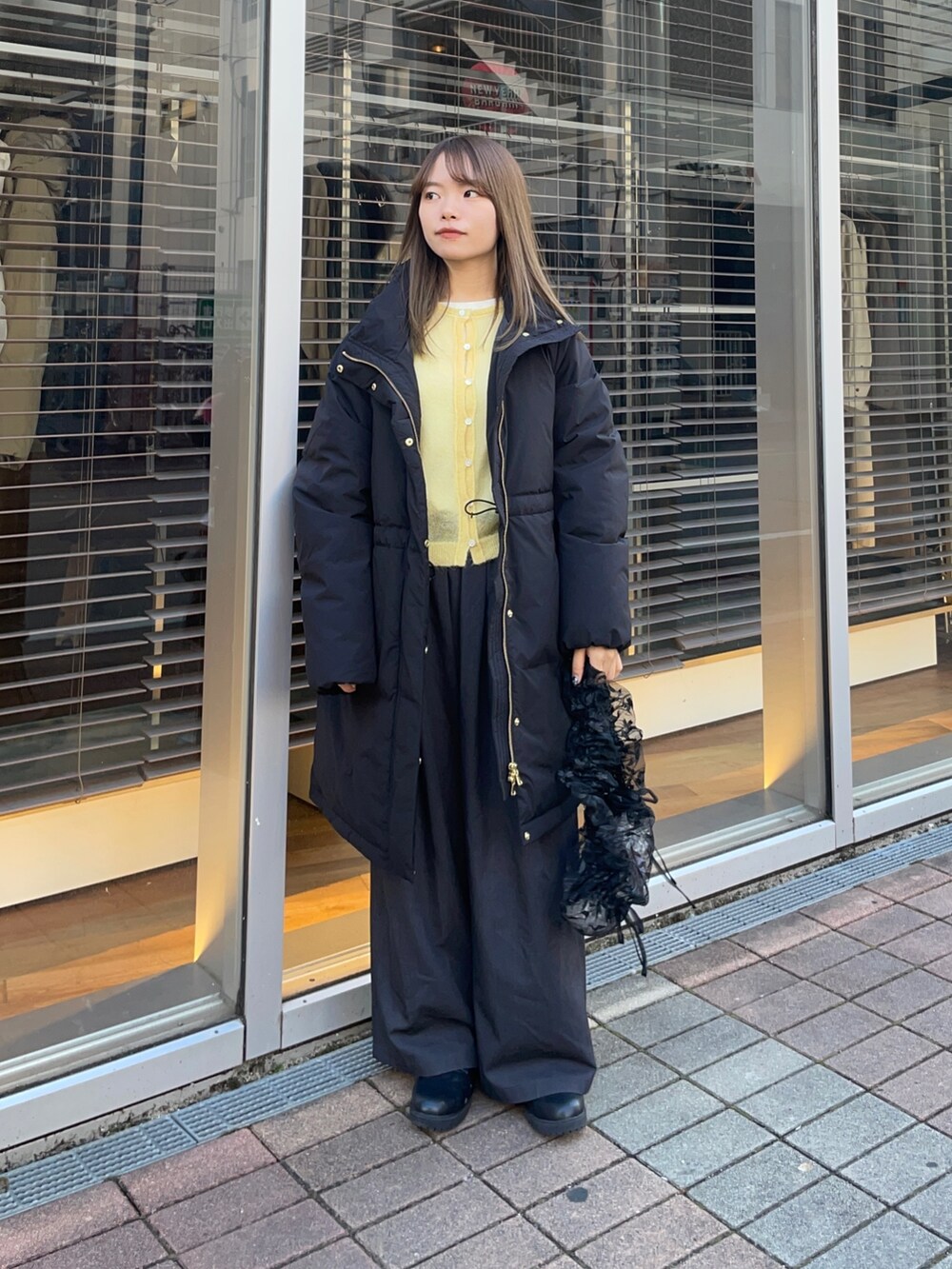 イエロー系のカーディガン/ボレロ、ホワイト系のTシャツ/カットソー、ブラック系のダウンジャケット/コートを着用したレディースの冬コーディネートの8枚目の写真