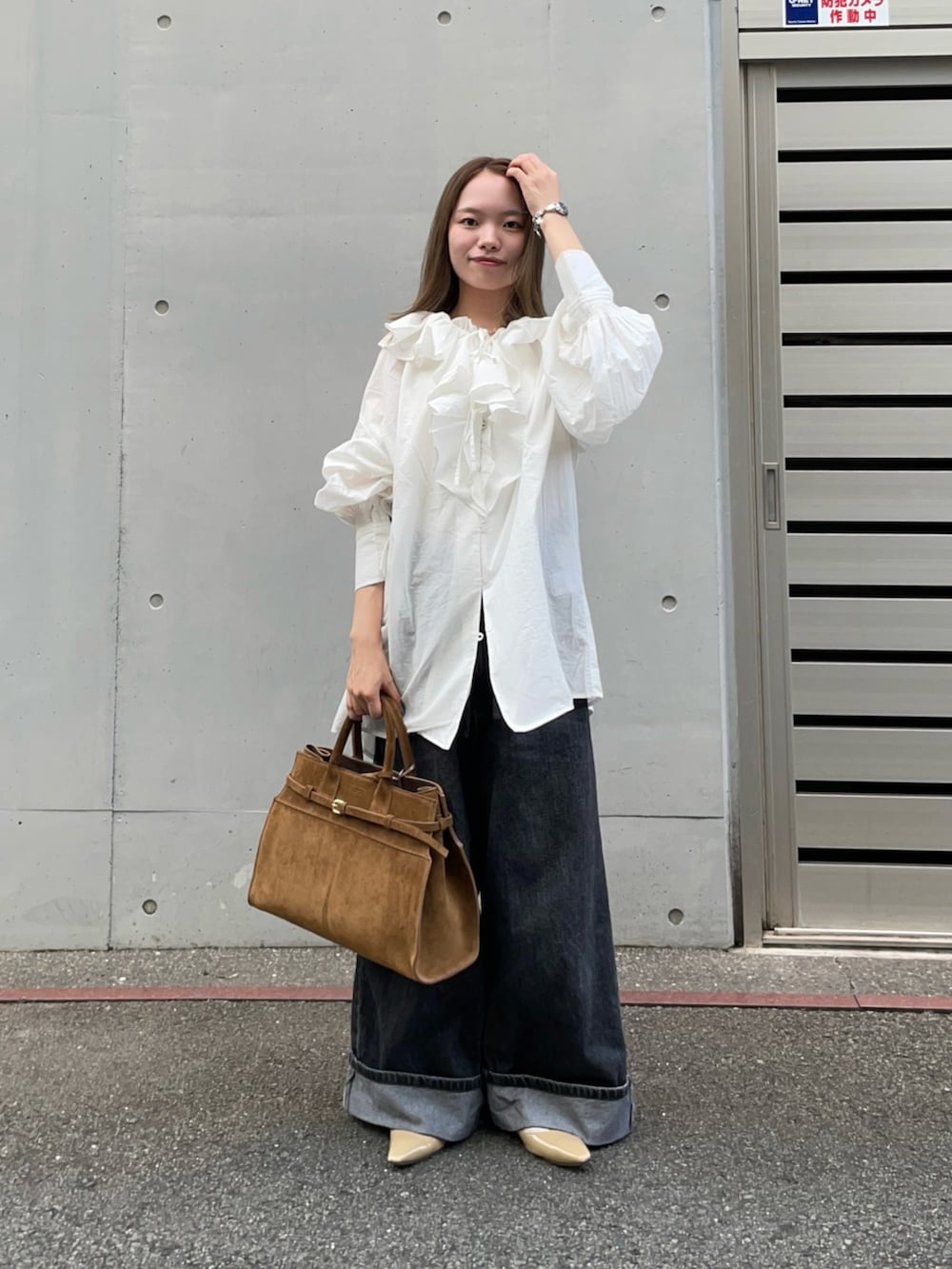 ブラウン系のトートバッグ、ブラック系のデニムパンツ、ベージュ系のパンプスを着用したレディースの秋コーディネートの2枚目の写真