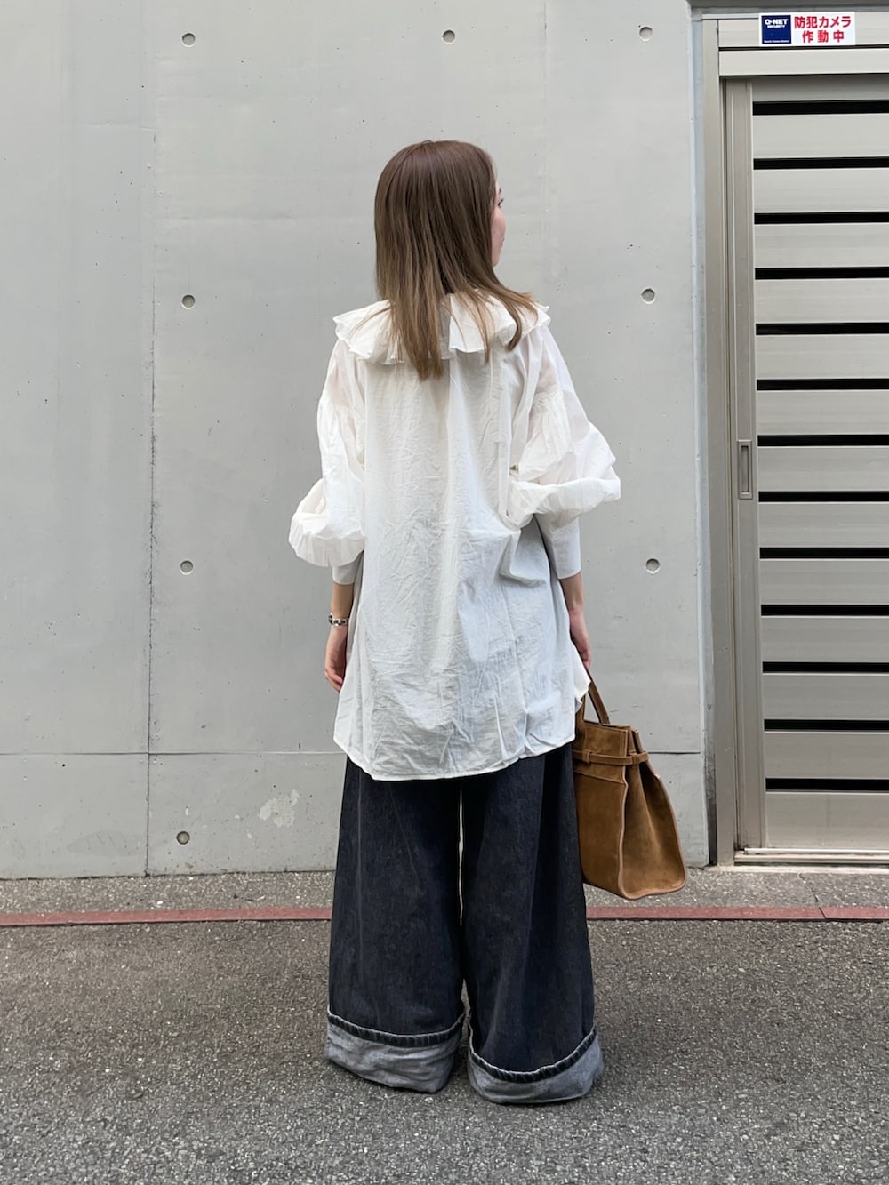 ブラウン系のトートバッグ、ブラック系のデニムパンツ、ベージュ系のパンプスを着用したレディースの秋コーディネートの4枚目の写真