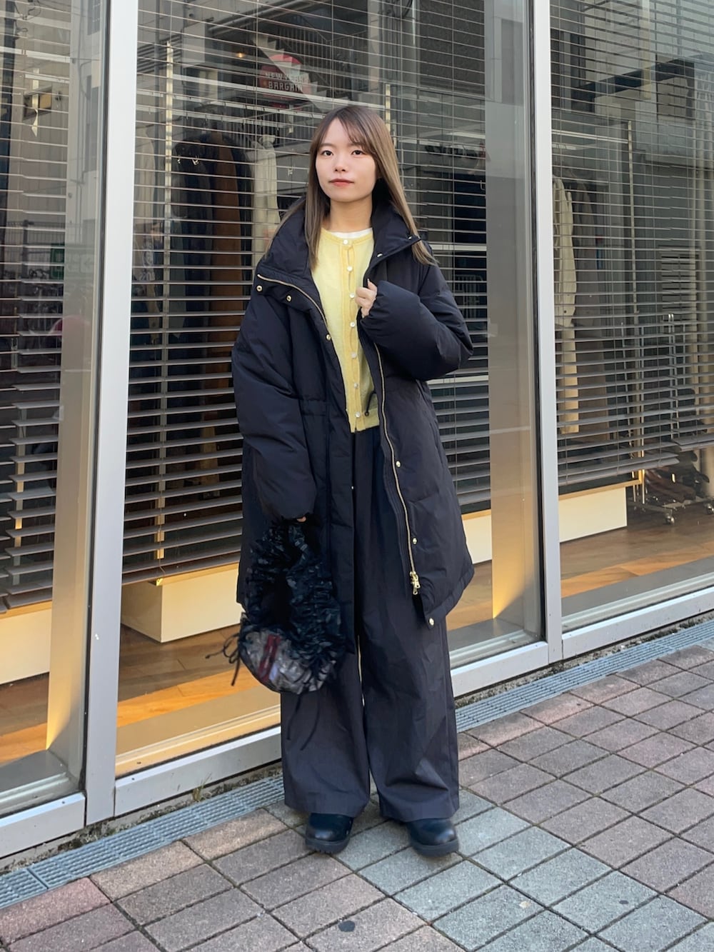 イエロー系のカーディガン/ボレロ、ホワイト系のTシャツ/カットソー、ブラック系のダウンジャケット/コートを着用したレディースの冬コーディネートの2枚目の写真