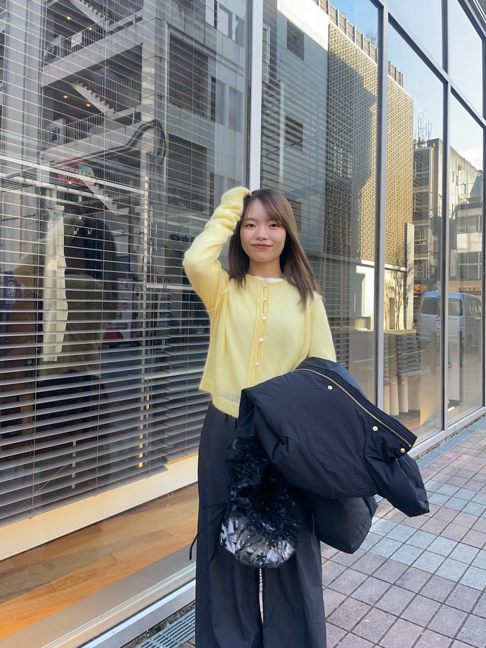 イエロー系のカーディガン/ボレロ、ホワイト系のTシャツ/カットソー、ブラック系のダウンジャケット/コートを着用したレディースの冬コーディネートの9枚目の写真