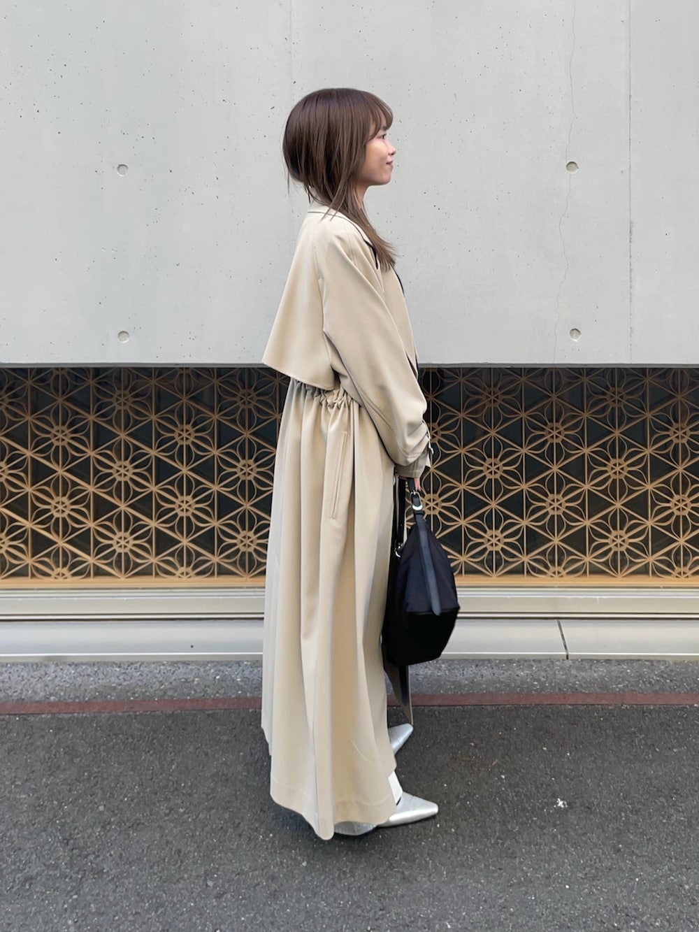 ベージュ系のトレンチコート、ブルー系のカーディガン/ボレロ、グレー系のデニムパンツを着用したレディースの冬コーディネートの5枚目の写真