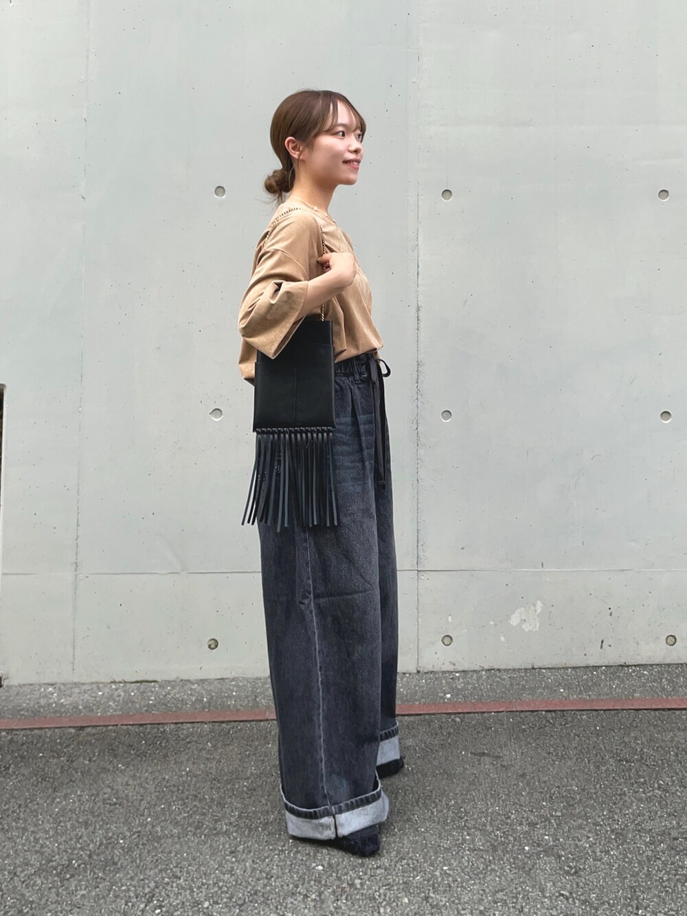 ブラック系のデニムパンツ、ベージュ系のTシャツ/カットソー、ブラック系のその他シューズを着用したレディースの秋コーディネートの7枚目の写真