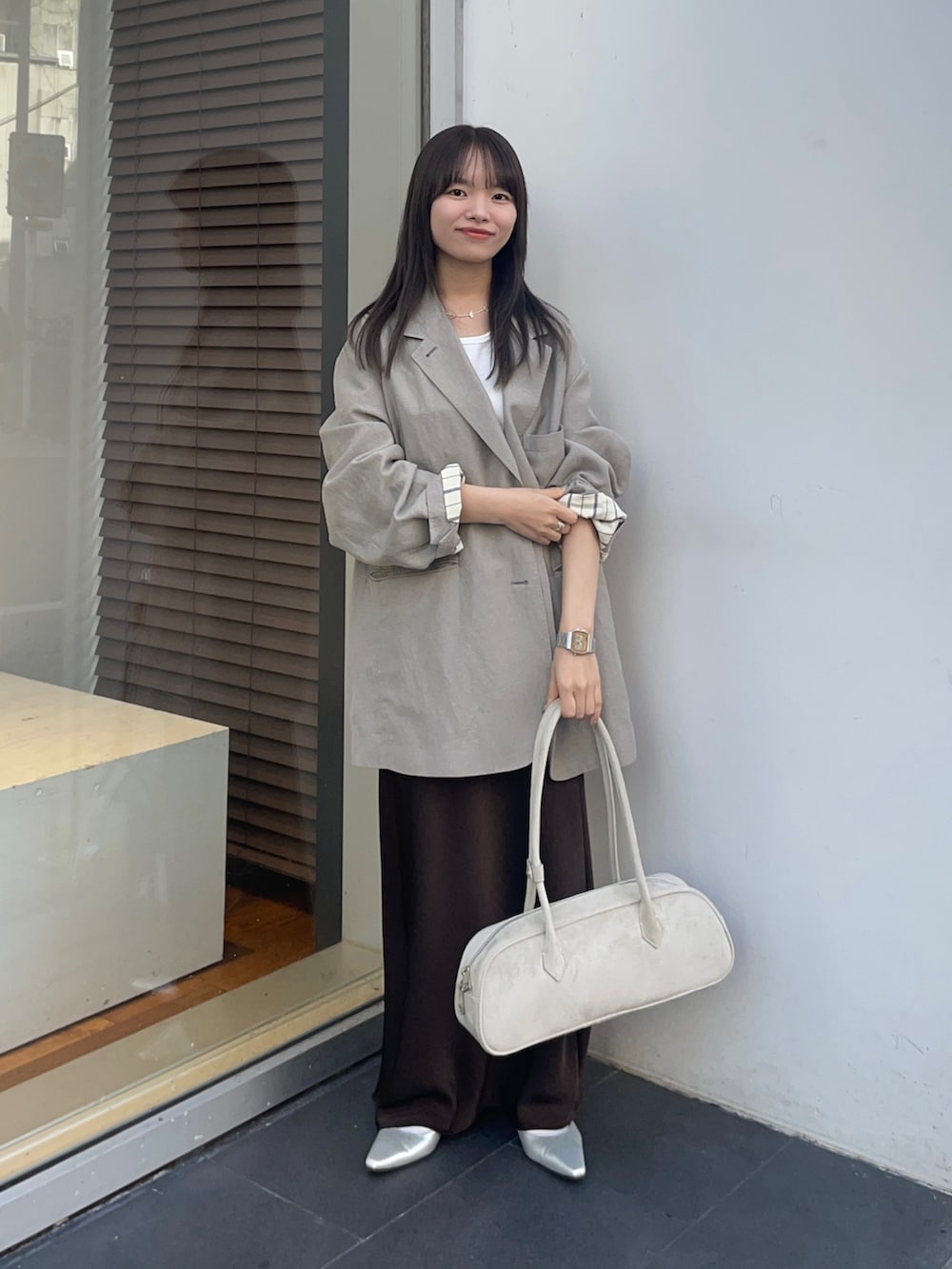 ベージュ系のその他アウター、ブラウン系のスカート、ホワイト系のタンクトップを着用したレディースの春コーディネートの6枚目の写真