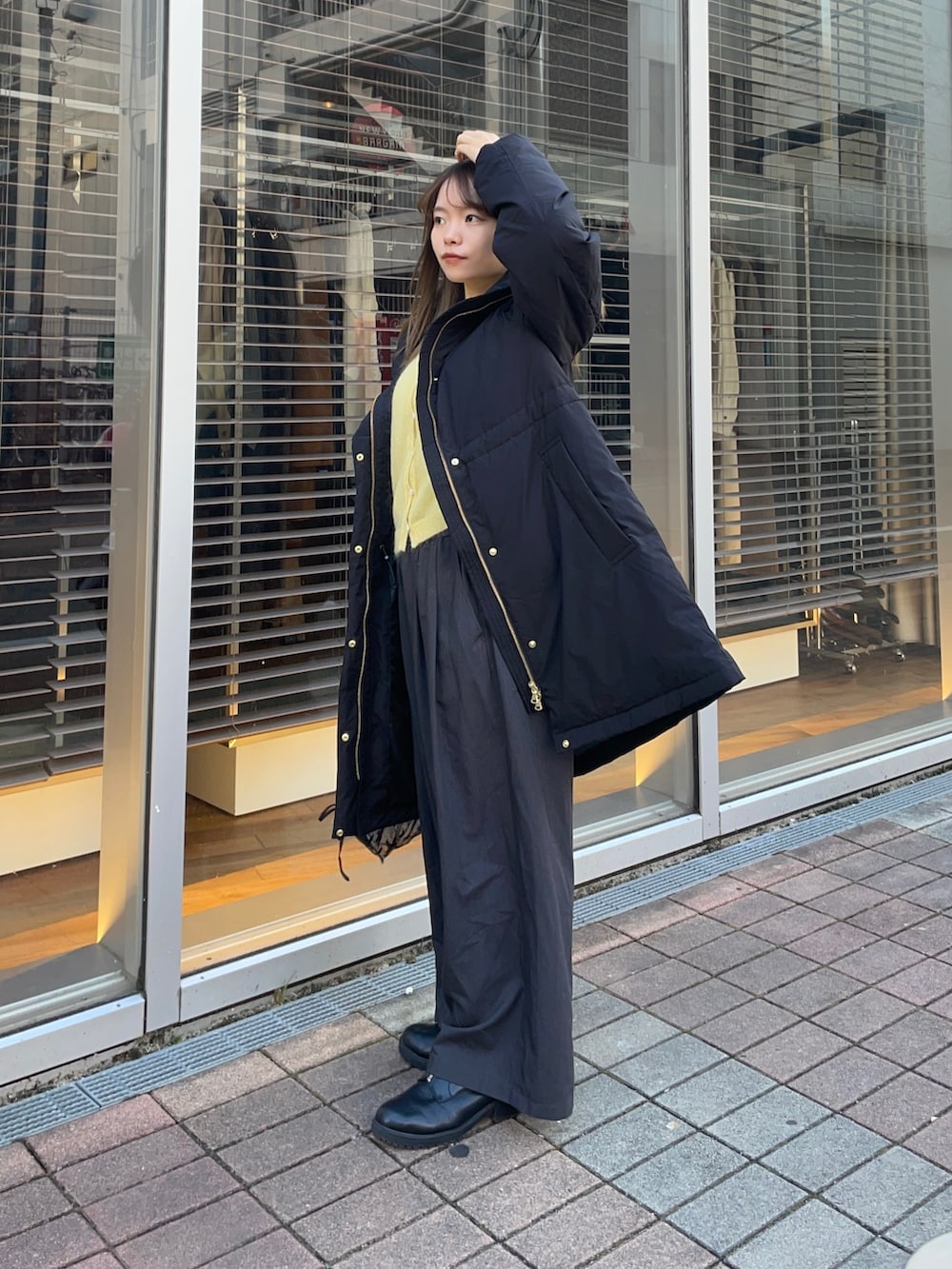 イエロー系のカーディガン/ボレロ、ホワイト系のTシャツ/カットソー、ブラック系のダウンジャケット/コートを着用したレディースの冬コーディネートの7枚目の写真