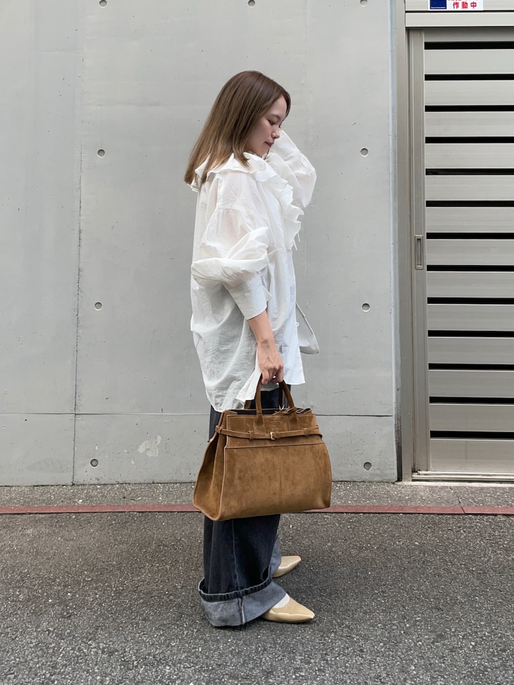 ブラウン系のトートバッグ、ブラック系のデニムパンツ、ベージュ系のパンプスを着用したレディースの秋コーディネートの3枚目の写真