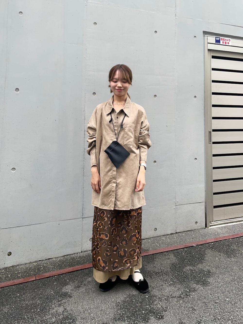 ベージュ系のシャツ/ブラウス、グリーン系のスカート、ブラック系のポーチを着用したレディースの夏コーディネートの2枚目の写真