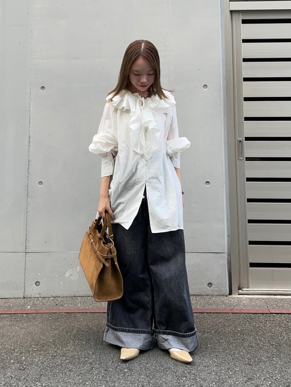 ブラウン系のトートバッグ、ブラック系のデニムパンツ、ベージュ系のパンプスを着用したレディースの秋コーディネートの7枚目の写真