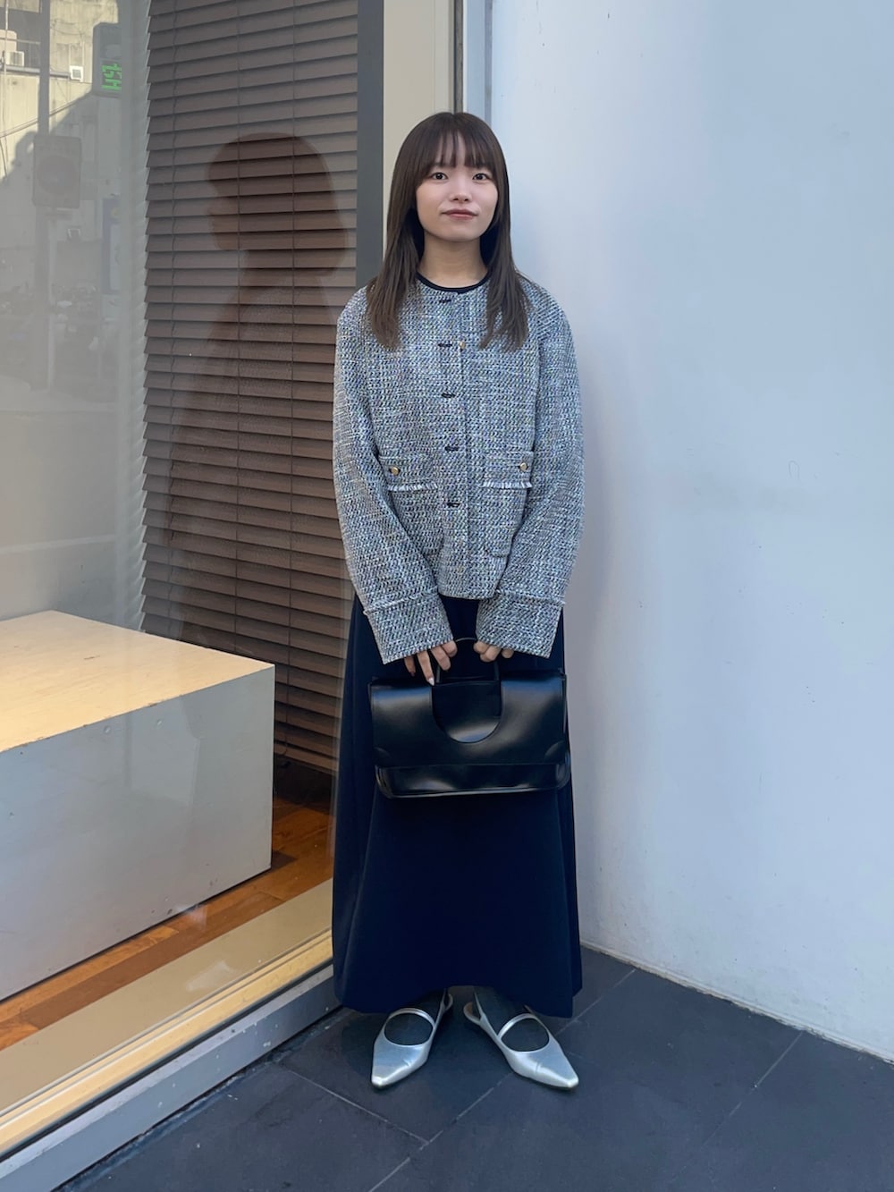 ブラック系のノーカラージャケット、ブルー系のワンピース、シルバー系のパンプスを着用したレディースの冬コーディネートの2枚目の写真