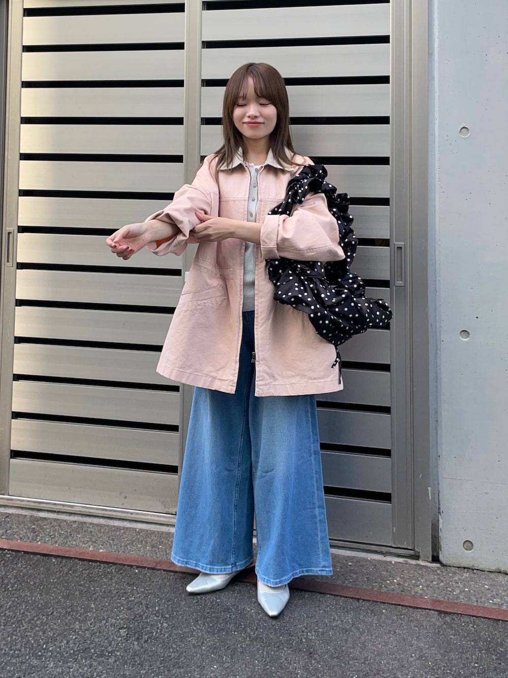 ピンク系のカバーオール、ブラック系のショルダーバッグ、ホワイト系のニット/セーターを着用したレディースの春コーディネートの2枚目の写真