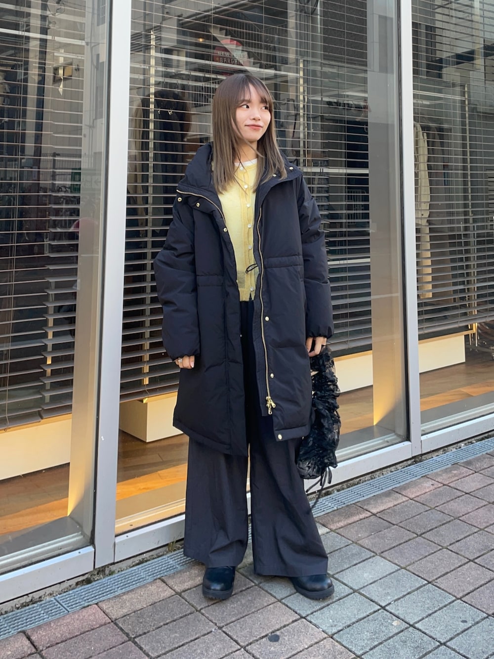 イエロー系のカーディガン/ボレロ、ホワイト系のTシャツ/カットソー、ブラック系のダウンジャケット/コートを着用したレディースの冬コーディネートの3枚目の写真