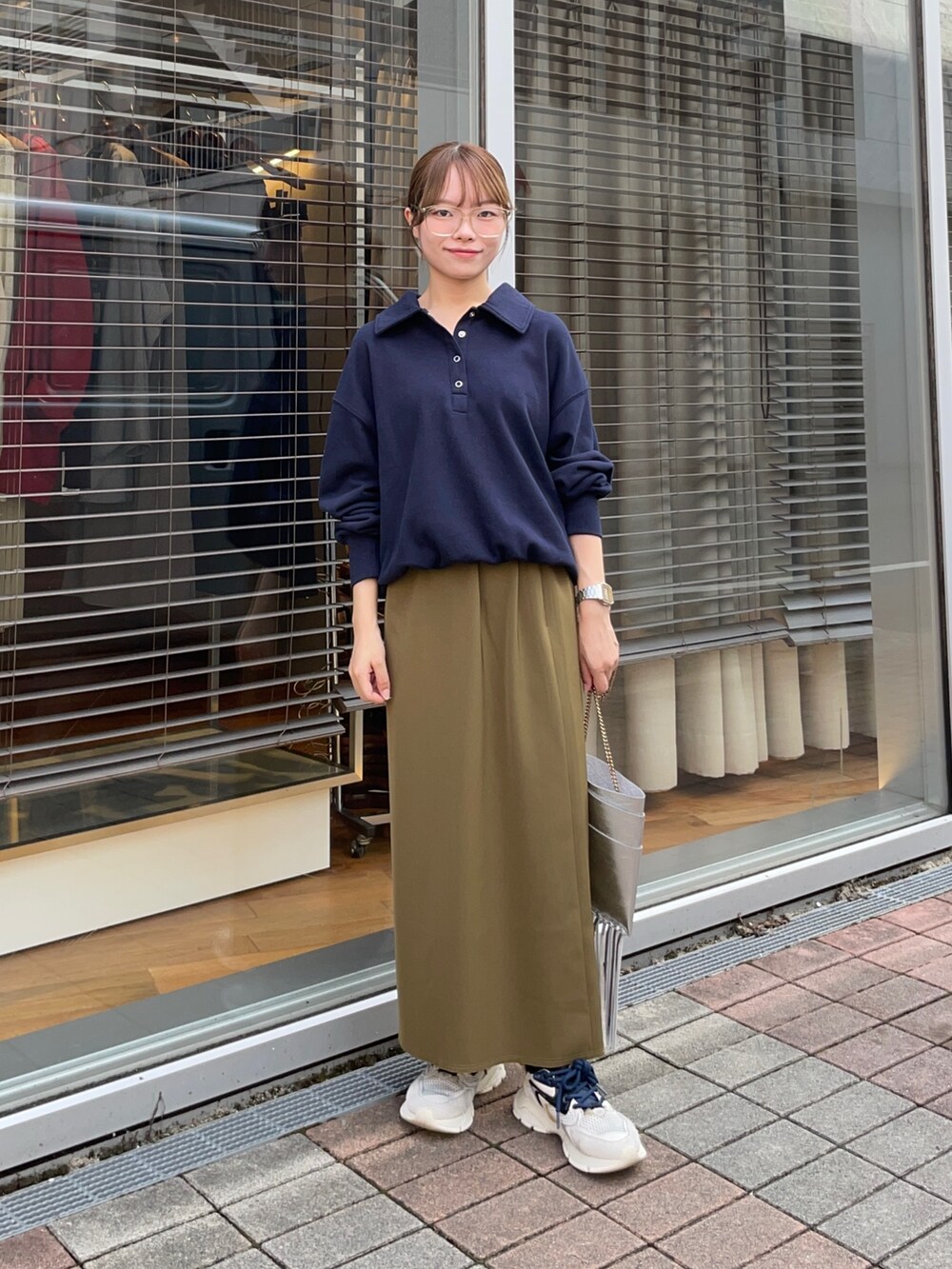 ブルー系のスウェット、グリーン系のスカート、シルバー系のショルダーバッグを着用したレディースの秋コーディネートの2枚目の写真