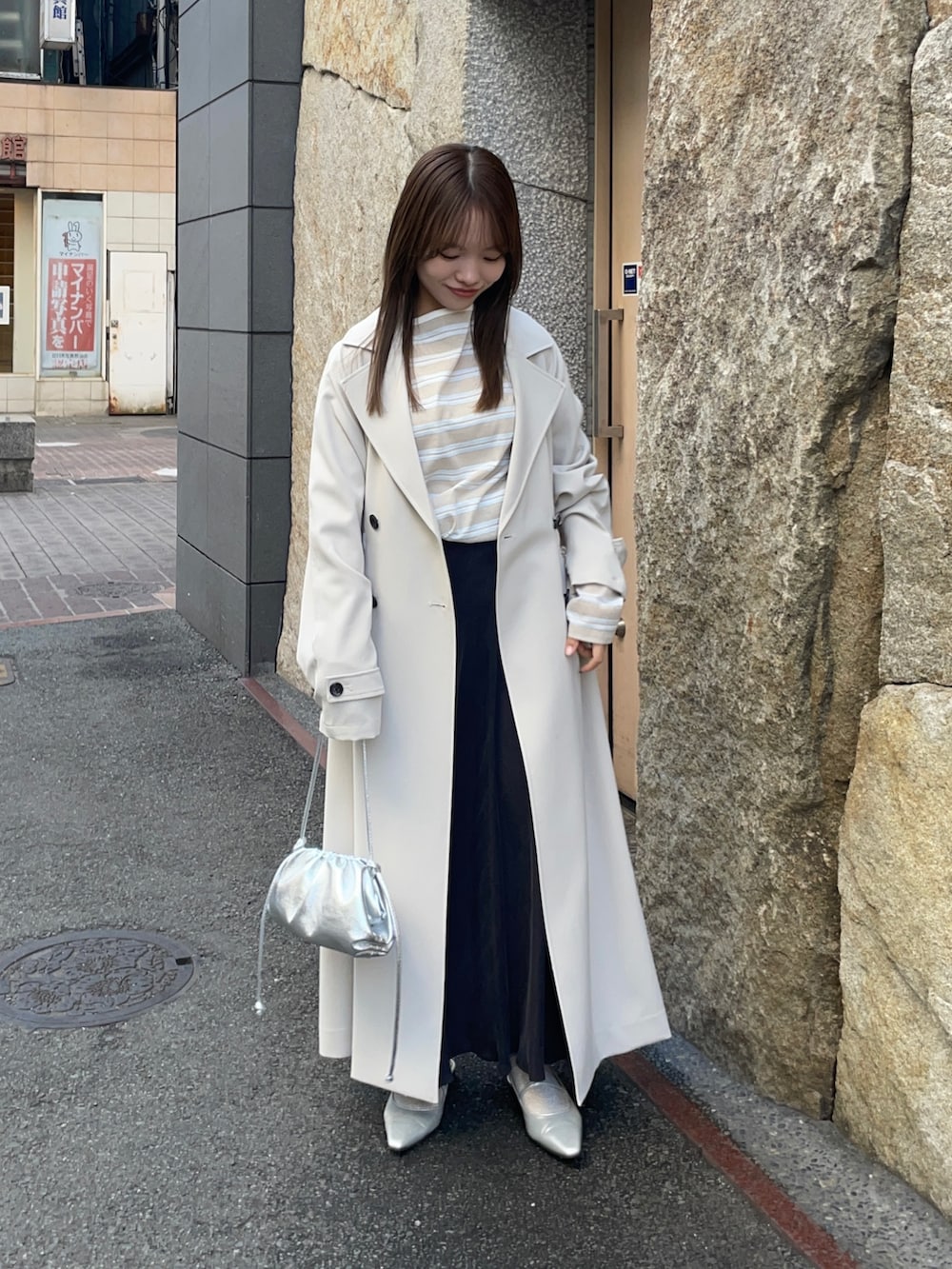 ベージュ系のTシャツ/カットソー、ブラック系のスカート、シルバー系のショルダーバッグを着用したレディースの春コーディネートの6枚目の写真