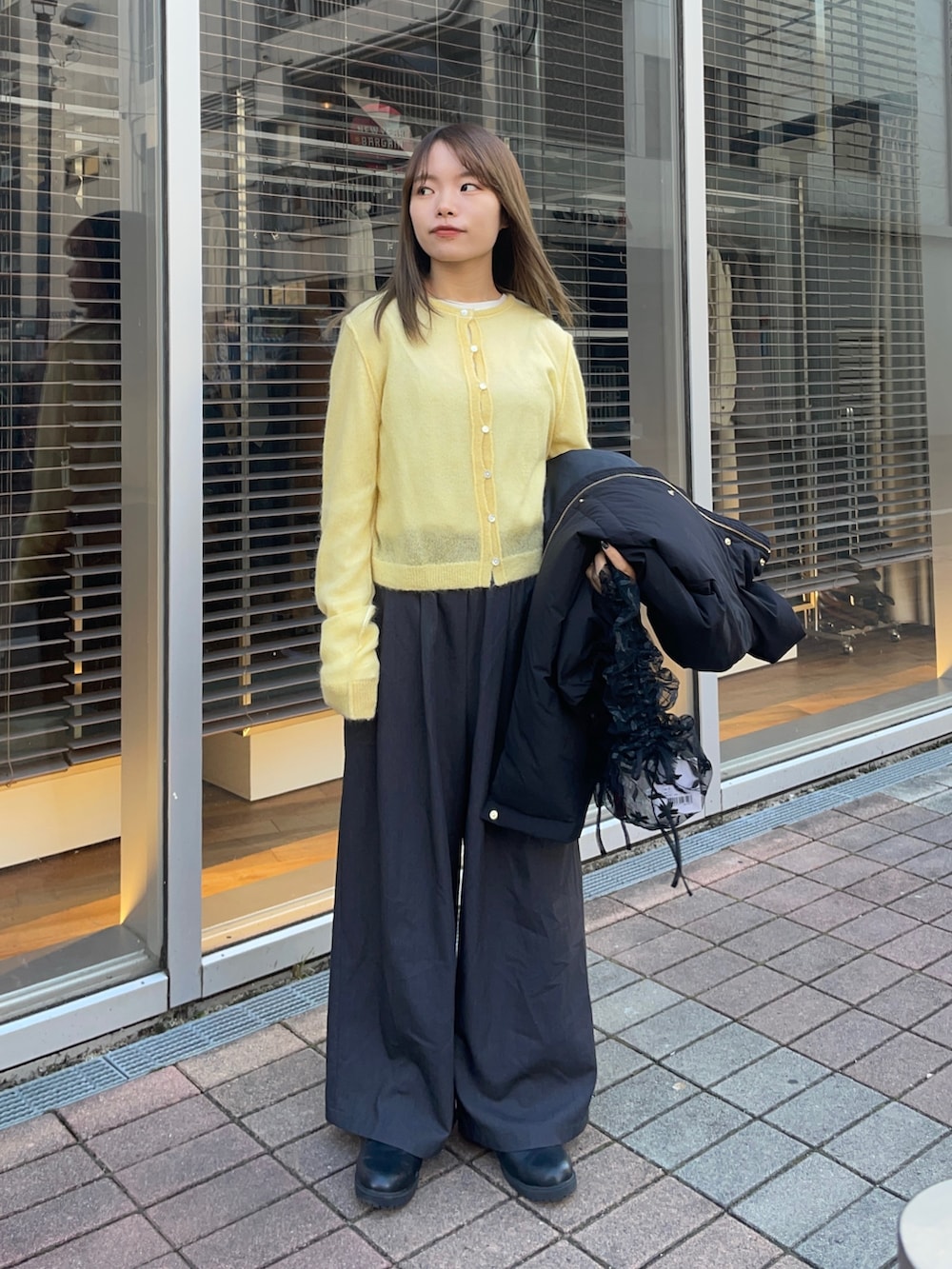 イエロー系のカーディガン/ボレロ、ホワイト系のTシャツ/カットソー、ブラック系のダウンジャケット/コートを着用したレディースの冬コーディネートの10枚目の写真