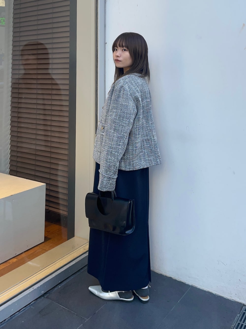 ブラック系のノーカラージャケット、ブルー系のワンピース、シルバー系のパンプスを着用したレディースの冬コーディネートの3枚目の写真