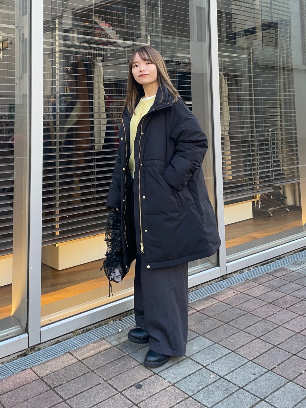 イエロー系のカーディガン/ボレロ、ホワイト系のTシャツ/カットソー、ブラック系のダウンジャケット/コートを着用したレディースの冬コーディネートの6枚目の写真