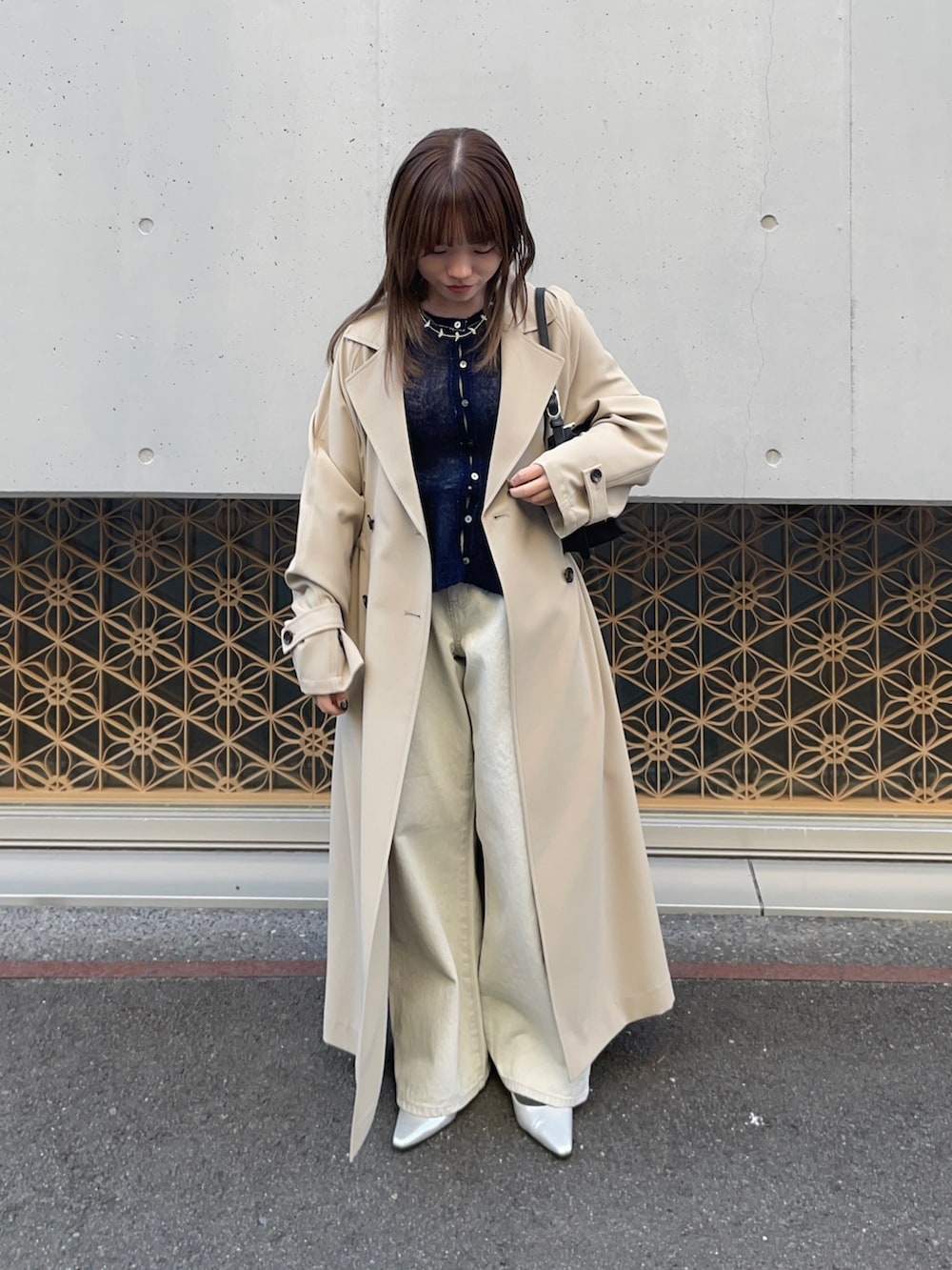 ベージュ系のトレンチコート、ブルー系のカーディガン/ボレロ、グレー系のデニムパンツを着用したレディースの冬コーディネートの2枚目の写真