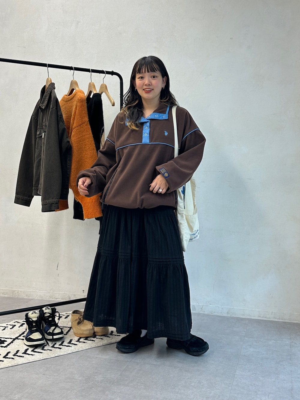 ブラウン系のTシャツ/カットソー、ホワイト系のトートバッグ、ブラック系のスカートを着用したレディースの秋コーディネートの2枚目の写真