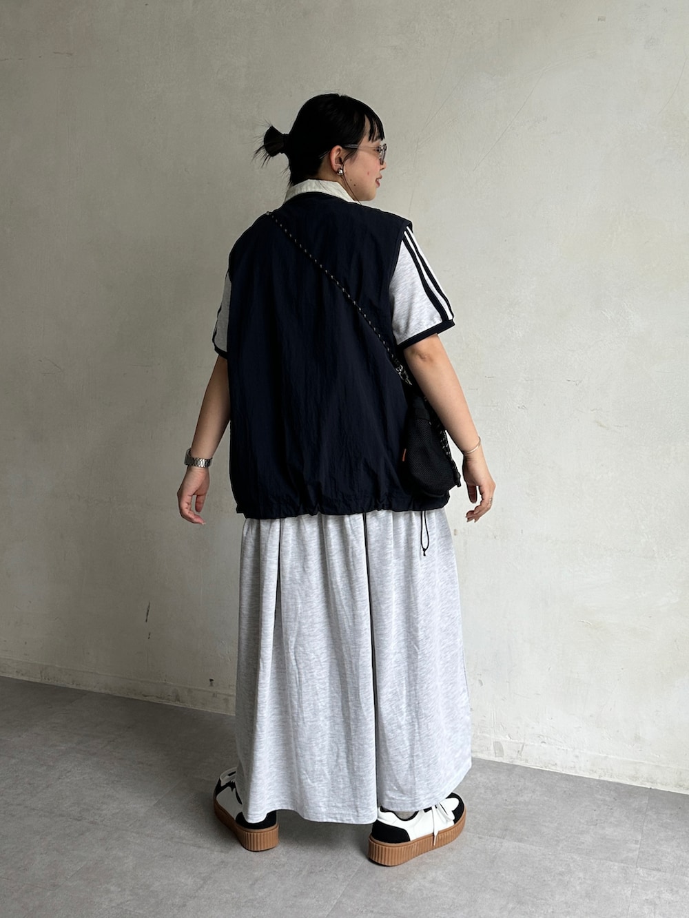 グレー系のワンピース、ブルー系のベスト、ブラック系のショルダーバッグを着用したレディースの春コーディネートの3枚目の写真