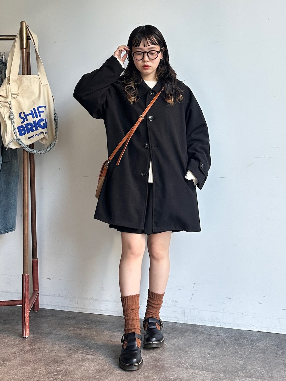 ブラック系のその他アウター、ベージュ系のショルダーバッグを着用したレディースの秋コーディネートの2枚目の写真