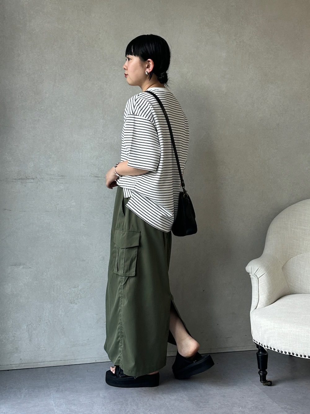 グリーン系のスカート、ブラック系のサンダル、ホワイト系のTシャツ/カットソーを着用したレディースの夏コーディネートの2枚目の写真